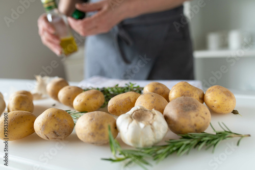 Raw potatoes with herbs and garlic on a white cutting board. Healthy eating background