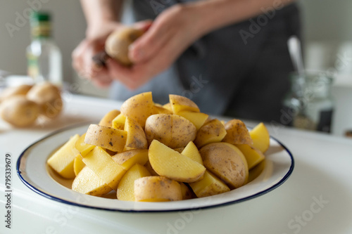 Woman preparing raw potatoes in the kitchen