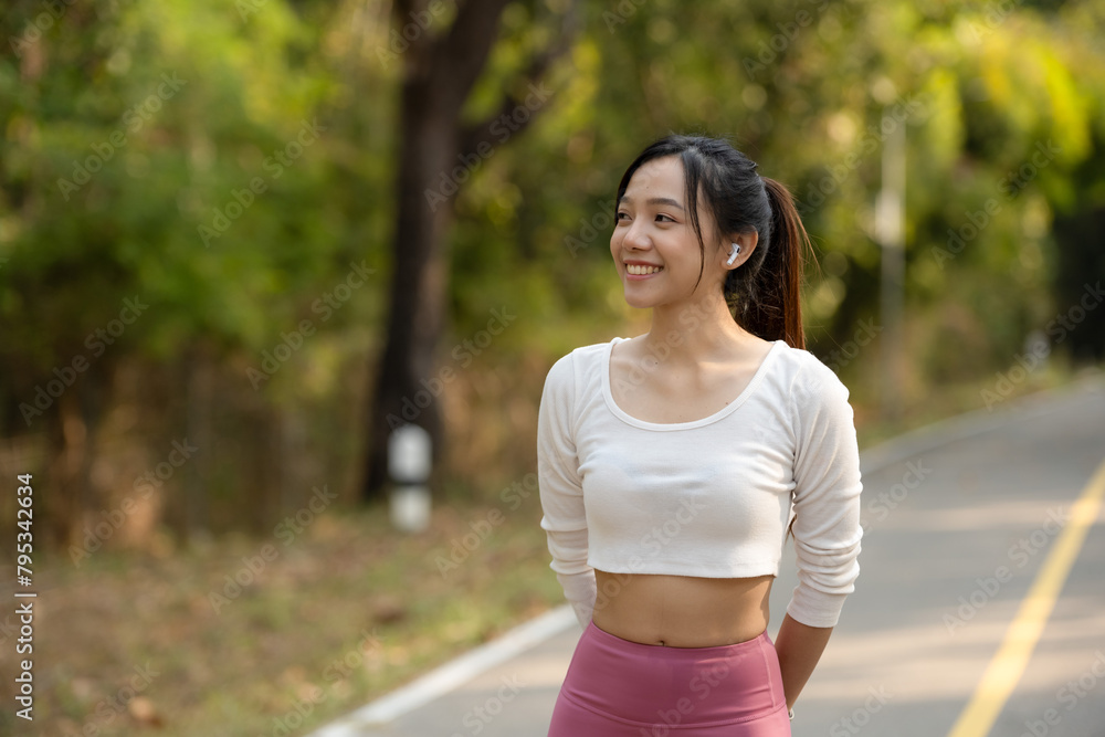 Happy athletic woman with crossed arms wearing a fitness smartwatch on a sunny park pathway. Happy athletic woman with crossed arms wearing a fitness smartwatch on a sunny park pathway.