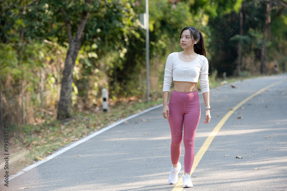 Happy athletic woman with crossed arms wearing a fitness smartwatch on a sunny park pathway. Happy athletic woman with crossed arms wearing a fitness smartwatch on a sunny park pathway.