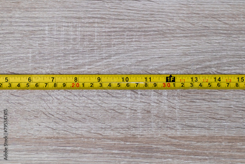 Metal tape measure on a wooden background