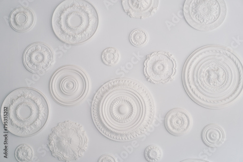 A collection of artistic white circular bas-relief sculptures with various patterns is arranged against a pristine white backdrop, showcasing a minimalist aesthetic with an emphasis on textures