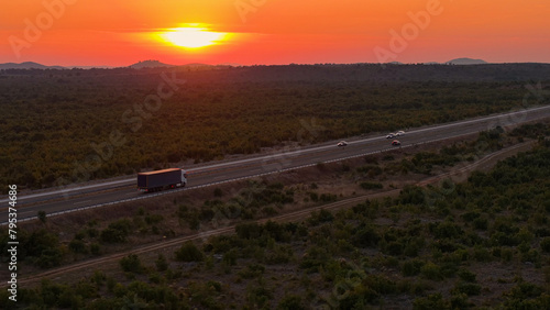 AERIAL: Scenic view of cargo truck driving along highway on sunny summer evening