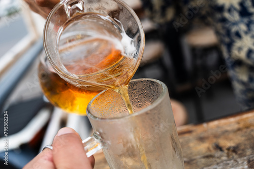 Hand of bartender pouring beer to glass. Beer pour from glass jar