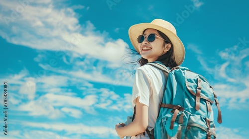 Portrait of an asian female tourist is traveling around the world carrying a backpack against a bright sky background