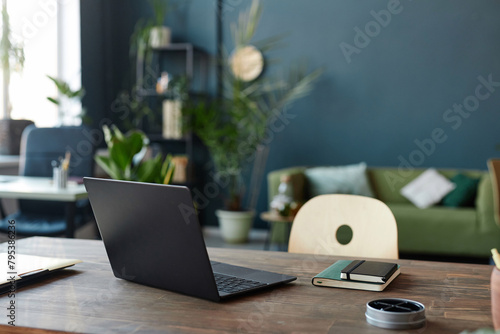 Background image of open laptop at workplace table in office with blue wall copy space 