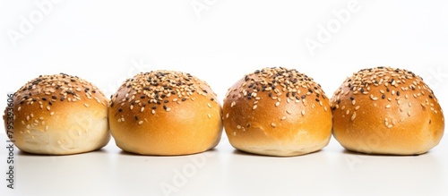 Four buns with sesame seeds lined up in a row