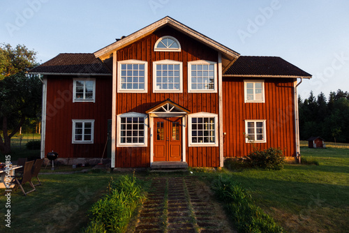 rotes Haus in Schweden bei Sonnenuntergang auf grüner Wiese © Salvatore