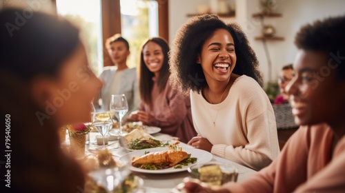 Happy young African American woman and her mother laugh while gathering with family for Thanksgiving at warm home.