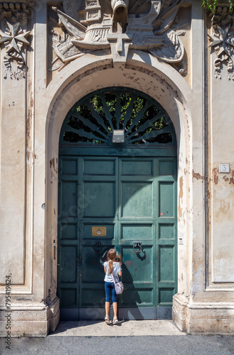 Little girl on tiptoe looking at St. Peter's dome from the hole of the door of Villa del Priorato of Malta on Aventino Hill at Knights of Malta square, Rome, Italy