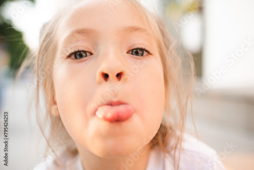 Close up portrait of baby girl 3-5 year old showing tongue outdoors