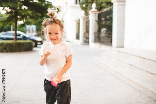 Smiling baby girl 4-5 year old wearing casual clothes over city street at background.