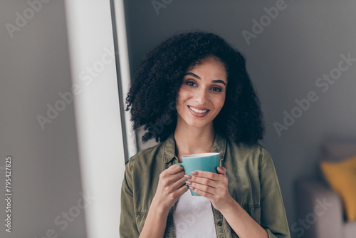 Portrait of pretty young woman toothy smile hold fresh coffee mug wear khaki shirt modern interior house indoors