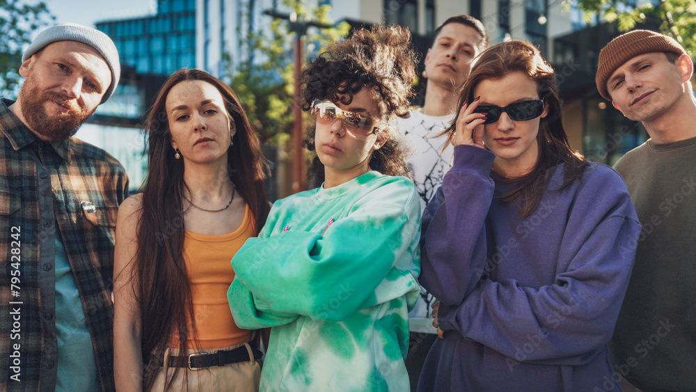 A Diverse Group Of Young Adults In Casual, Colorful Attire Stands Confidently In An Urban Setting, Showcasing A Mix Of Modern And Retro Fashion, Embodying Youth Culture And Friendship.