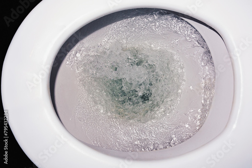 The toilet flushes clean water, close-up from above