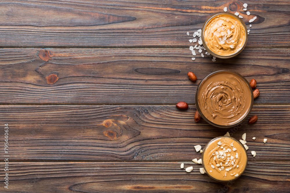 Fototapeta premium Glass jar with peanut butter on table background, top view space for text and close up