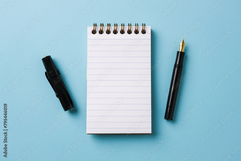 Top view of notebook and fountain pen on blue background Top view of notebook and fountain pen on blue background