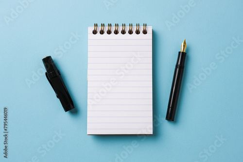 Top view of notebook and fountain pen on blue background © yalcinsonat