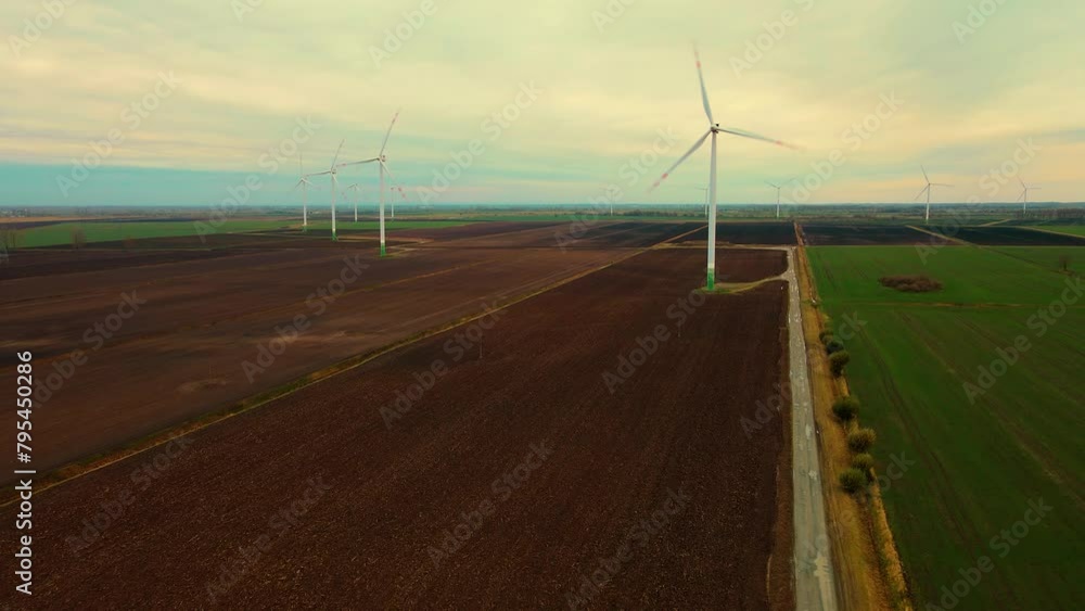 Energy producing wind turbines. Windmills with blades in field at cloudy day. Popularization of renewable energy sources and sustainable development Energy producing wind turbines. Windmills with blades in field at cloudy day. Popularization of renewable energy sources and sustainable development