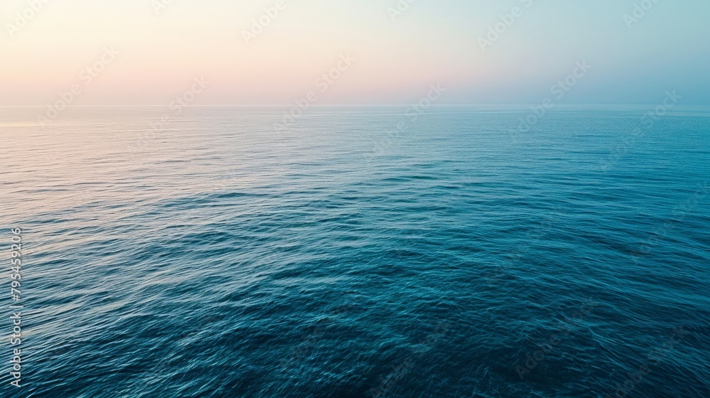 Obraz premium An aerial view of a calm sea at dawn, the subtle gradient of blues creating a tranquil, minimalist landscape that invites contemplation.