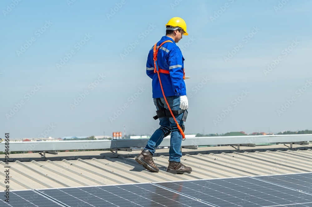 A solar panel installer walks across a roof inspecting the panels. A solar panel installer walks across a roof inspecting the panels.