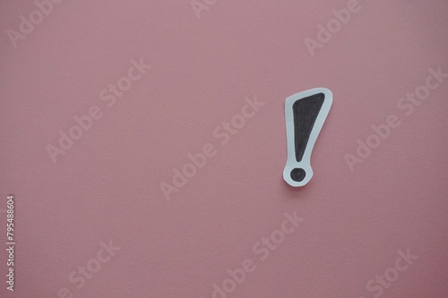 top view of of black exclamation mark on white speech bubble on a pink background.