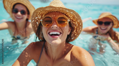 Woman in straw hat and orange sunglasses beams delightfully in a sunlit pool on a perfect summer day