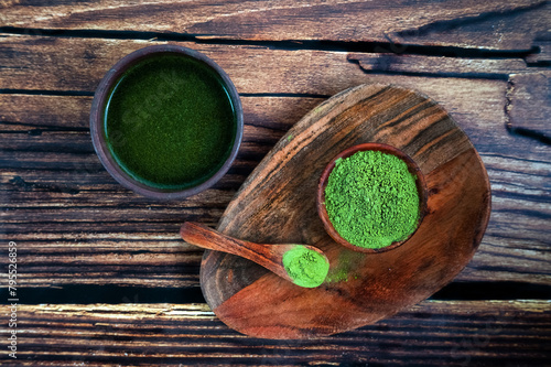 Matcha powder or spirulina or barley grass in a plate on a wooden background.