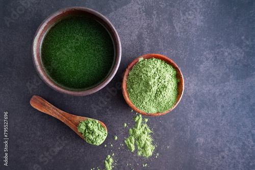 Green young barley grass powder in a bowl on a wooden background matcha or chlorella.