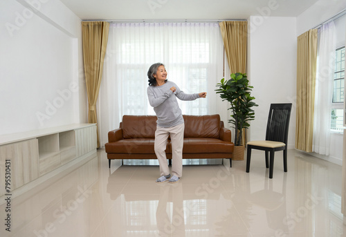 playful asian senior woman dancing in the living room,elderly lifestyle,domestic life,relaxation