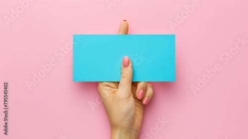  Woman's hand displays a blue document against pink backdrop, adorned with pink manicure