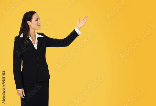 Profile image - smiling woman wear confident suit, showing at mock up slogan text empty blank place. Business ad concept. Isolated against yellow wall background. Wide banner image © vgstudio