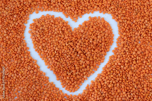 Heart of organic red lentils on white background. Top table view. Raw plant-based protein legumes, healthy food concept.