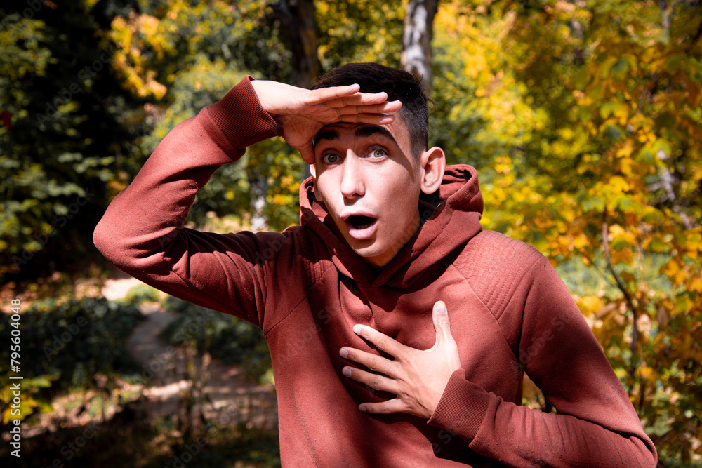 Obraz premium A young attractive guy is resting in the autumn forest.