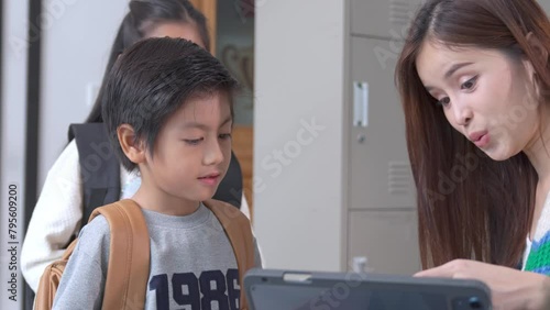 Smiling Asian female lecturer helping children student during classroom. Education knowledge, successful teamwork concept.