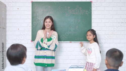 Asian teacher , question with group of children in classroom and raise their hands to answer in learning.