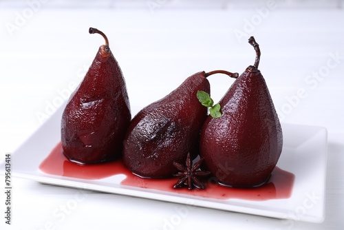 Tasty red wine poached pears with mint and anise on white wooden table, closeup