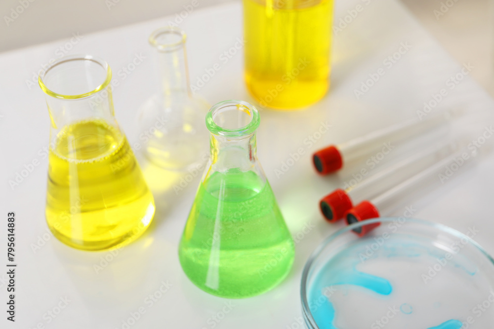 Laboratory analysis. Different glassware with liquids on white table Laboratory analysis. Different glassware with liquids on white table