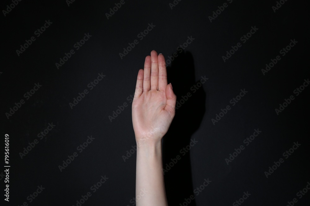 Fototapeta premium Woman showing open palm on black background, closeup