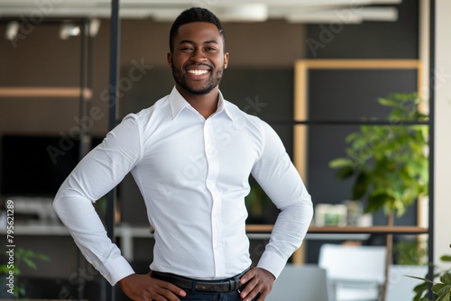 Smiling confident young black businessman looking at camera standing in office. Elegant stylish corporate leader successful ceo executive manager. © Adriana