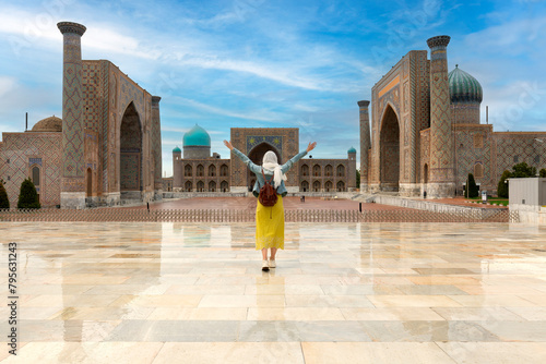 Uzbekistan, Samarcanda - young girl standing with open arms looking Registan square