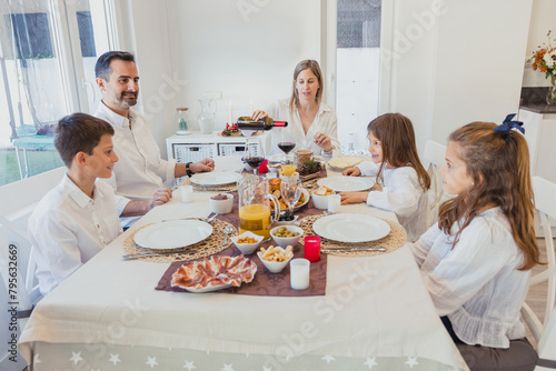Joyful family sharing Christmas meal at festively decorated table photo