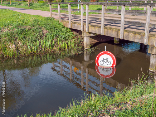 Prohibiting sign for cycling under a bridge in a water canal.
