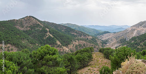 Panoramic view of a typical mountain landscape of Andalusia under a stormy sky. Malaga, Spain.
