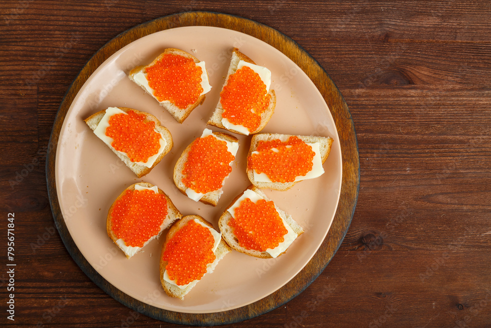 Sandwich with red caviar on a plate on a wooden table Sandwich with red caviar on a plate on a wooden table