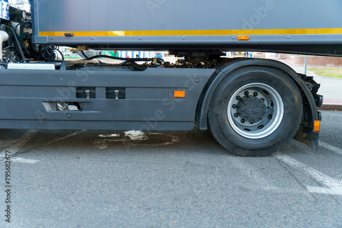 A new truck with a trailer on the road. Details of the truck in close-up. New headlights and wheels of the car. The concept of cargo transportation