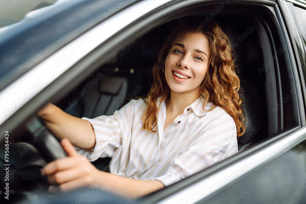 Young smiling woman driving a car drives around the city. Car travel, lifestyle, carshering concept. Young smiling woman driving a car drives around the city. Car travel, lifestyle, carshering concept.