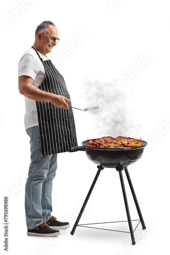 Mature man grilling meat on a barbecue