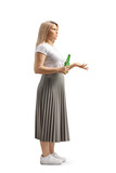 Full length profile shot of a young woman holding a bottle of beer