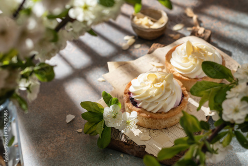 Sweet cream tarts on rustic wooden board in spring white flowers